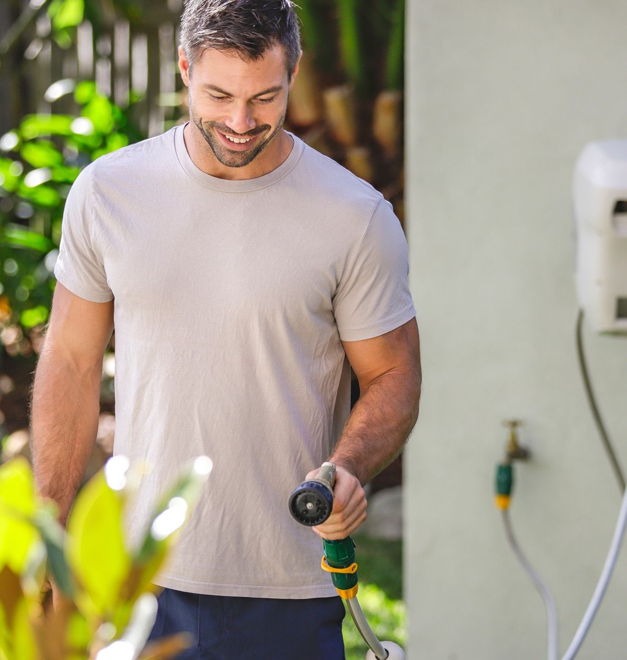 Man Watering Garden with Hose Reel